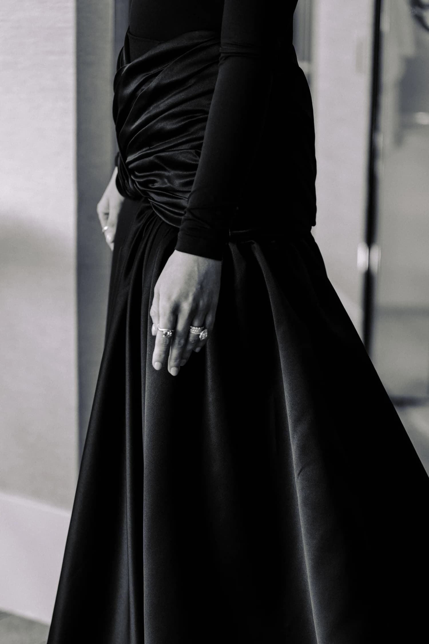 A close view of a hand, jewellery and gathered fabric on a black evening gown.