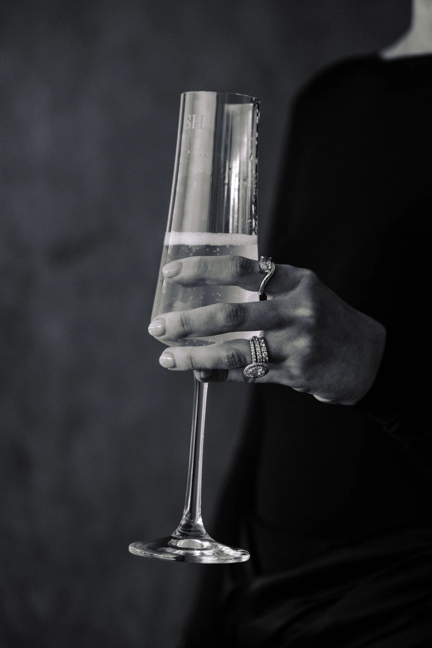 A hand holding a champagne flute against dark eveningwear.