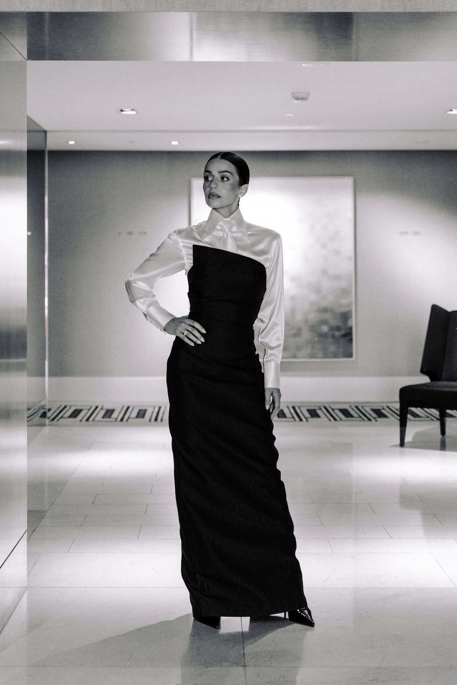 A woman standing with one hand on her hip in a white blouse and floor-length black gown at Crown Towers.