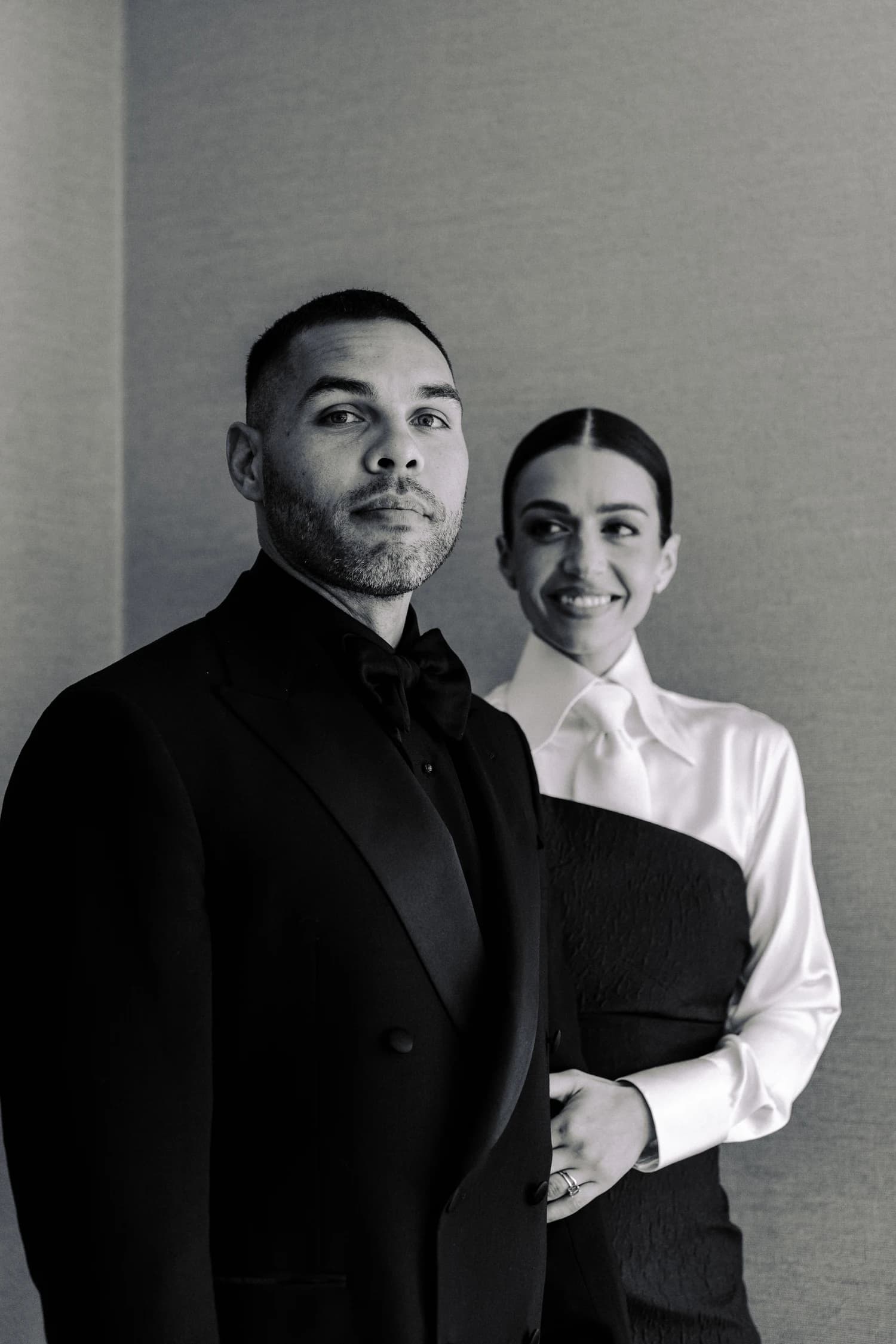 A man in a dark suit and a woman in a white blouse and black gown standing together for a portrait.
