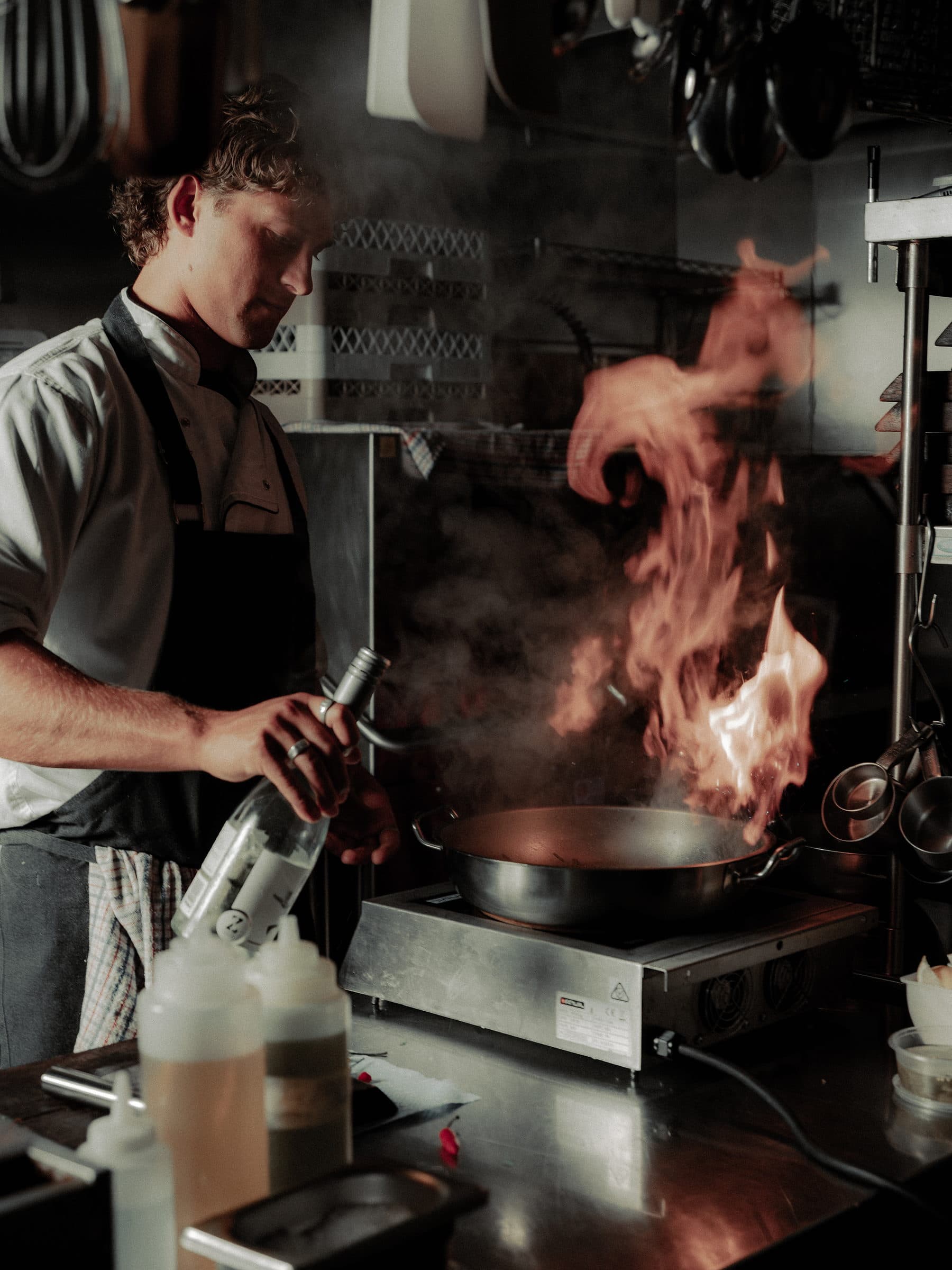 A chef flambeing a pan in the Circa 1884 kitchen