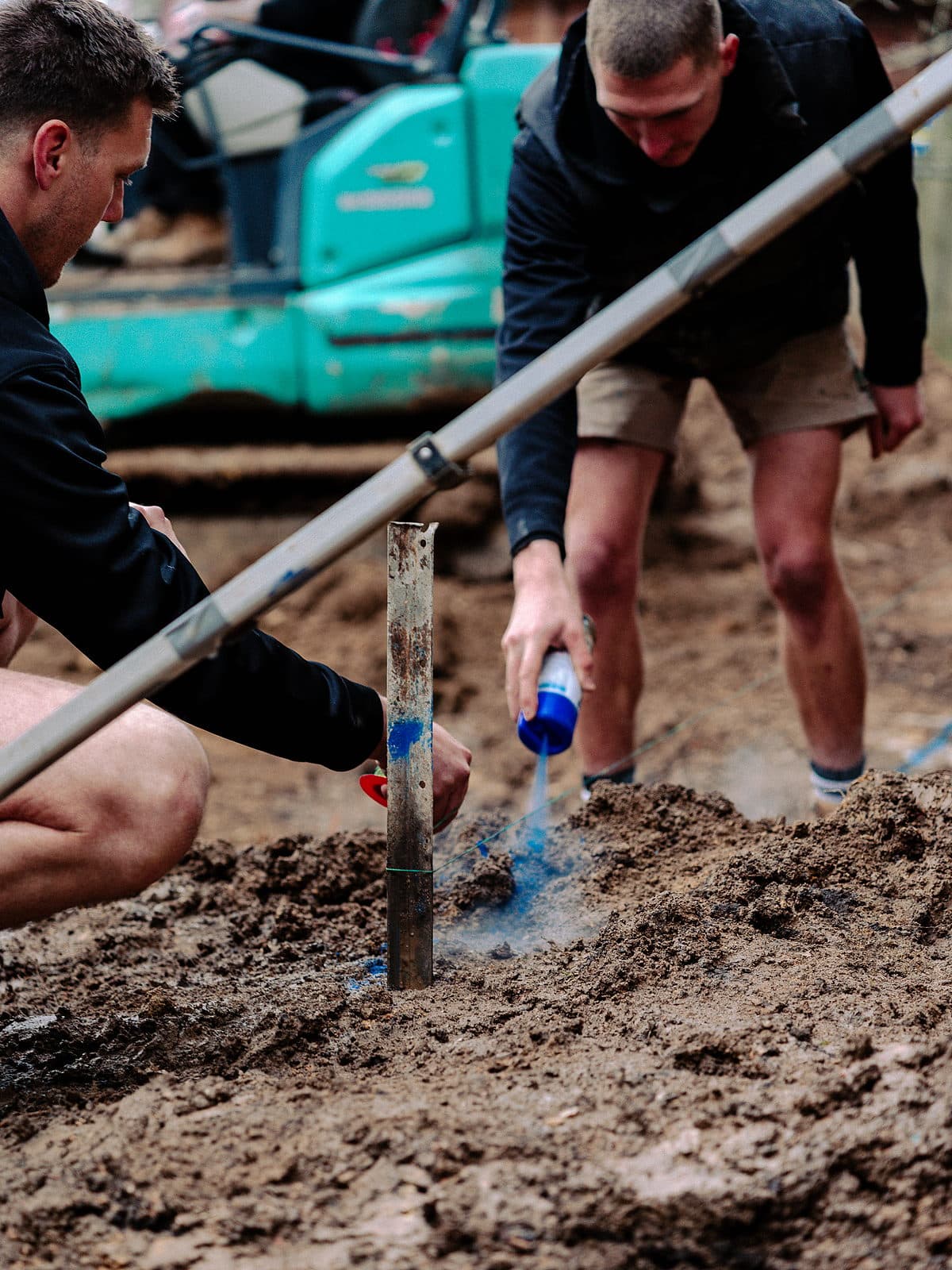 Two builders marking out a pool excavation in the mud