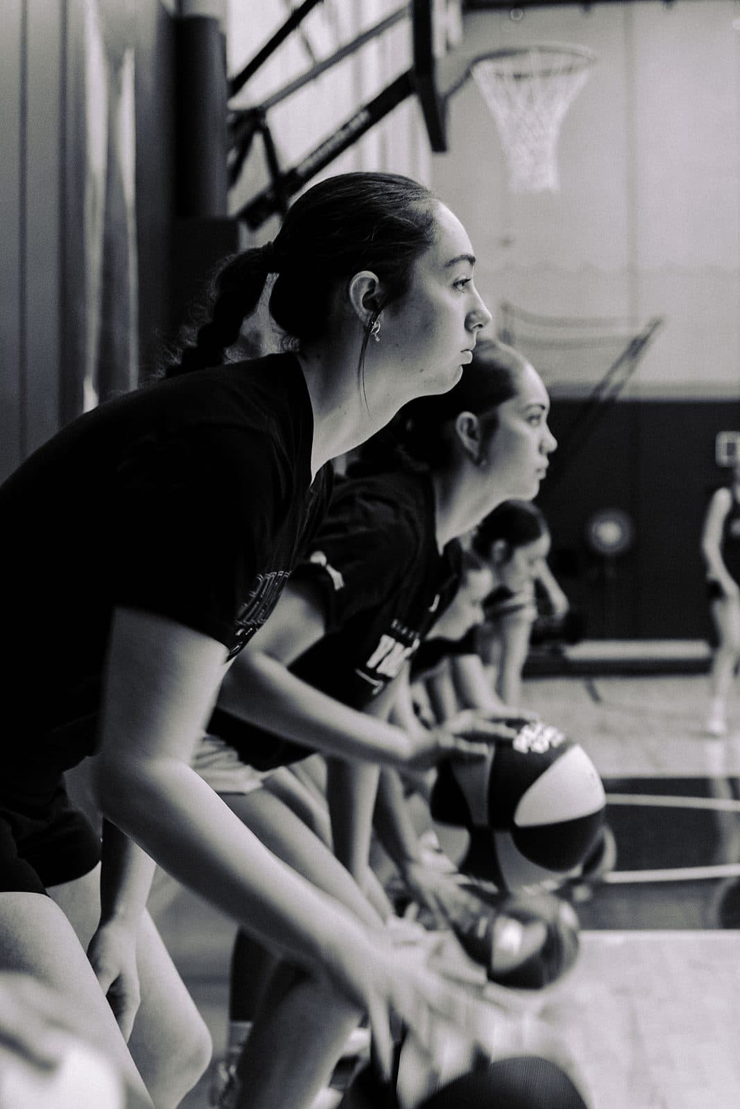 A line of junior basketball players holding a defensive stance at training