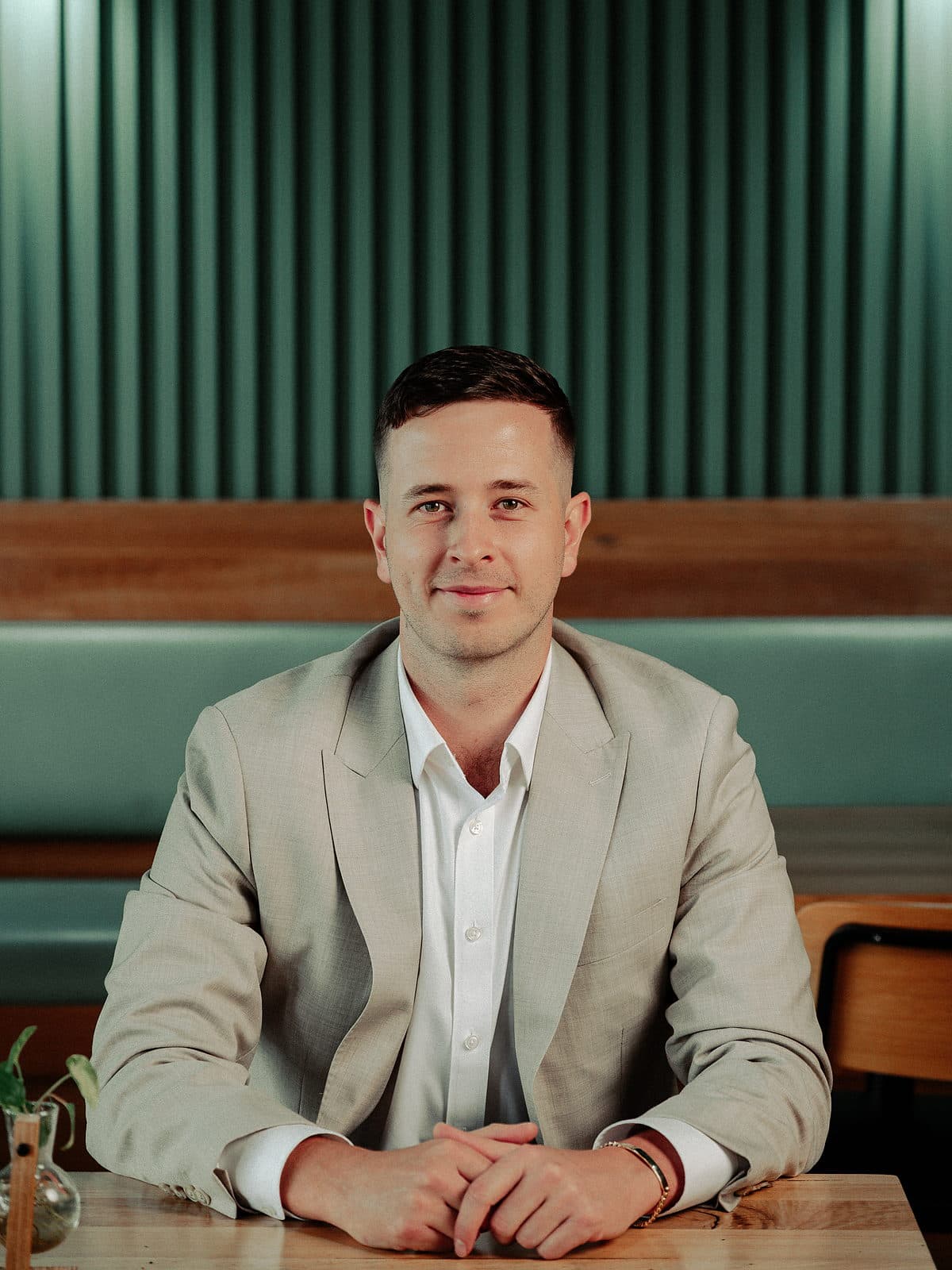 A mortgage broker seated at a cafe table, looking to camera