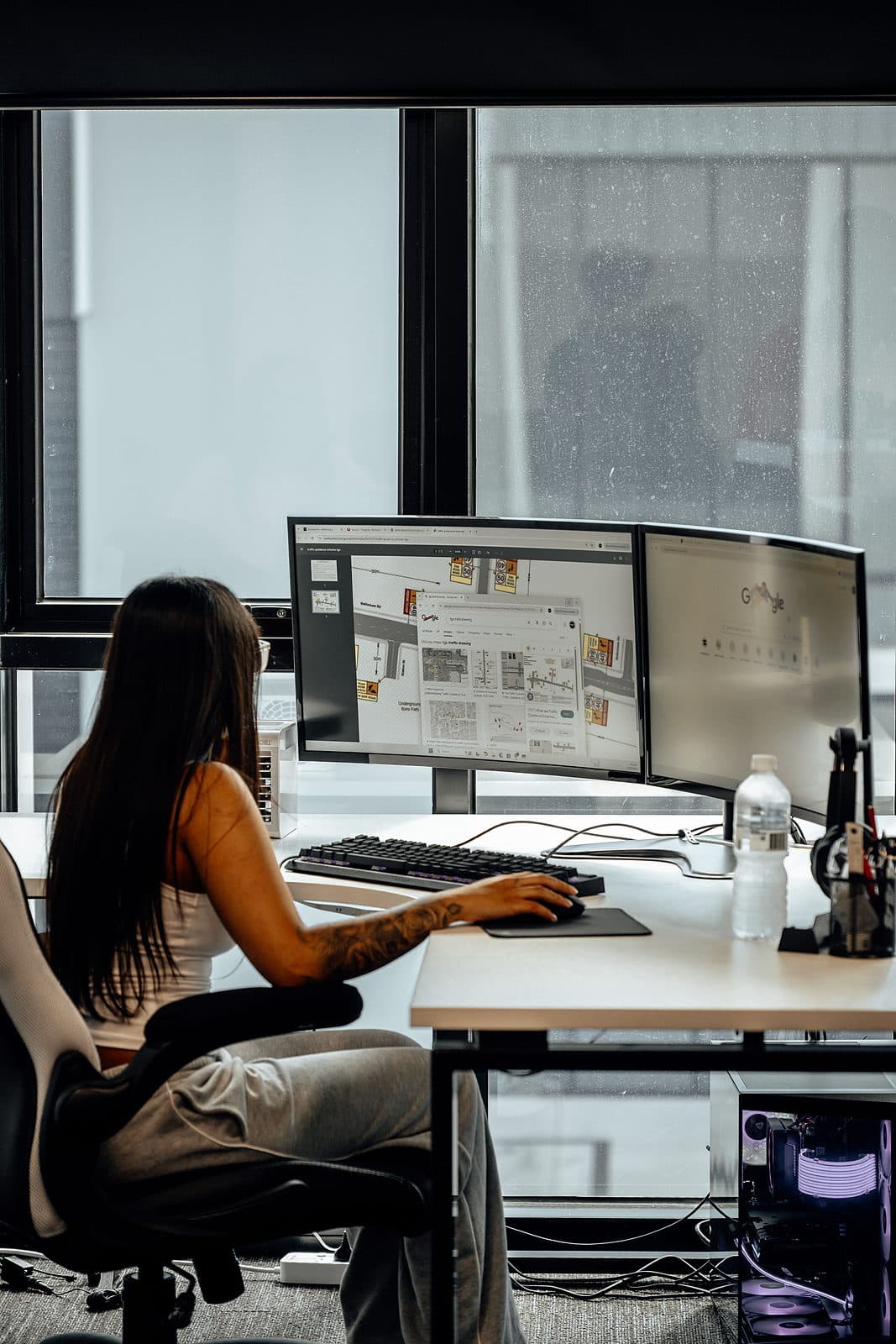 A planner drawing up a site plan at a dual monitor desk