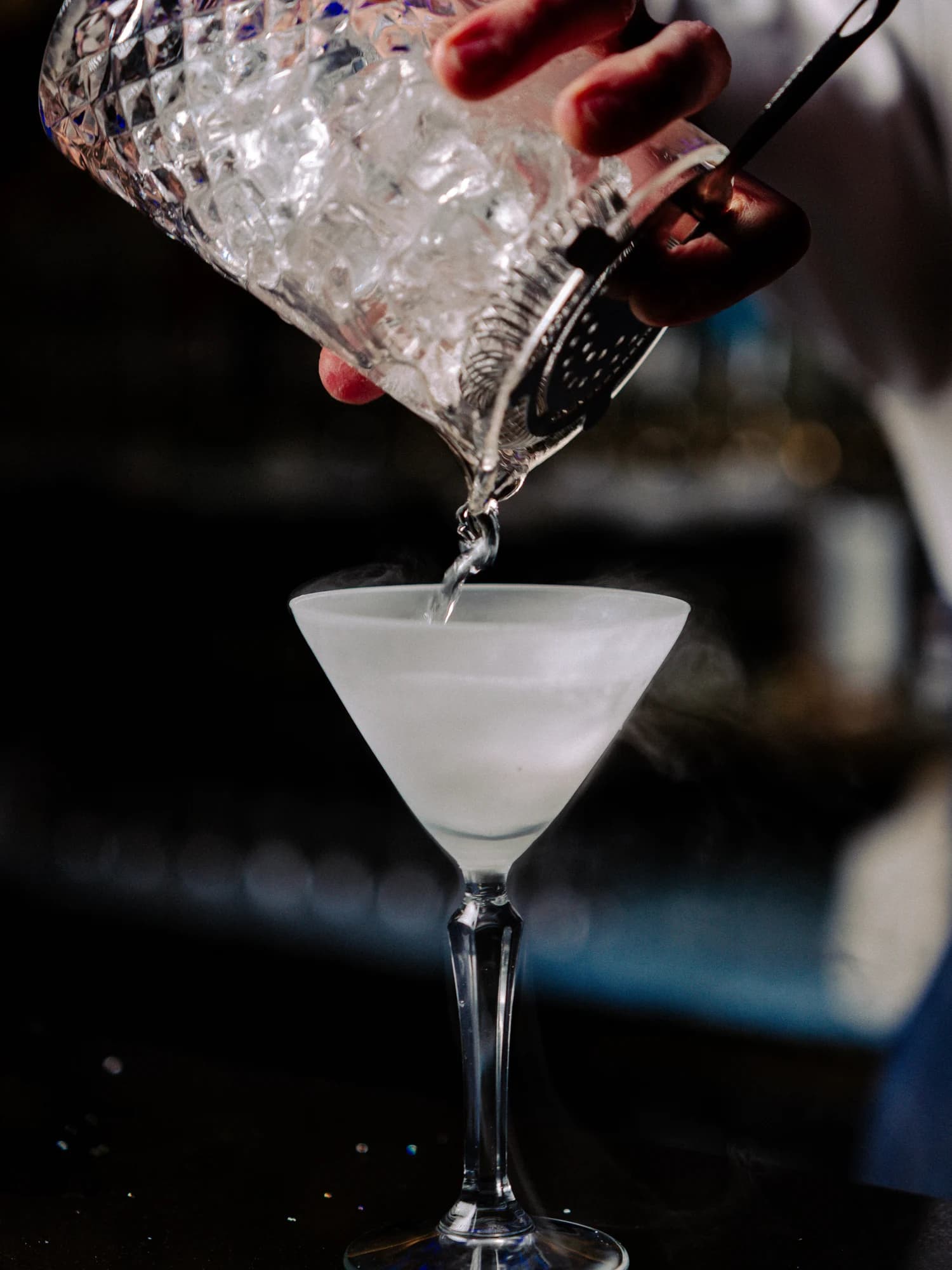 A cocktail being poured from a crystal mixing glass into a stemmed glass at Circa 1884.