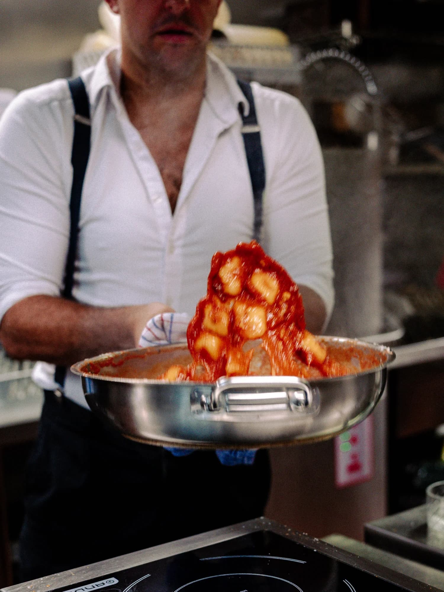 Circa 1884’s chef tossing gnocchi in tomato sauce in the kitchen.