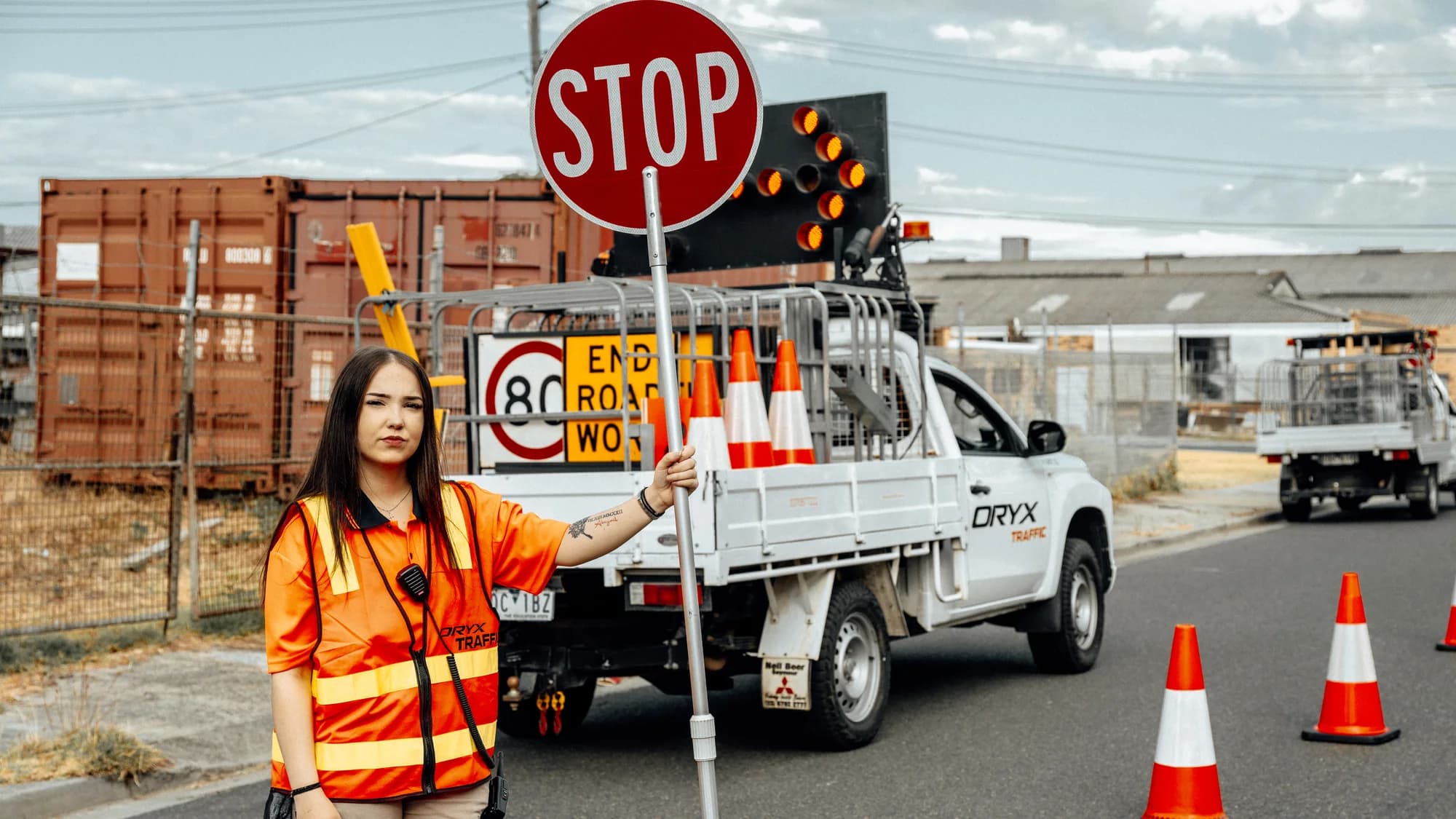 An Oryx Traffic team member with a stop sign beside the branded work vehicle
