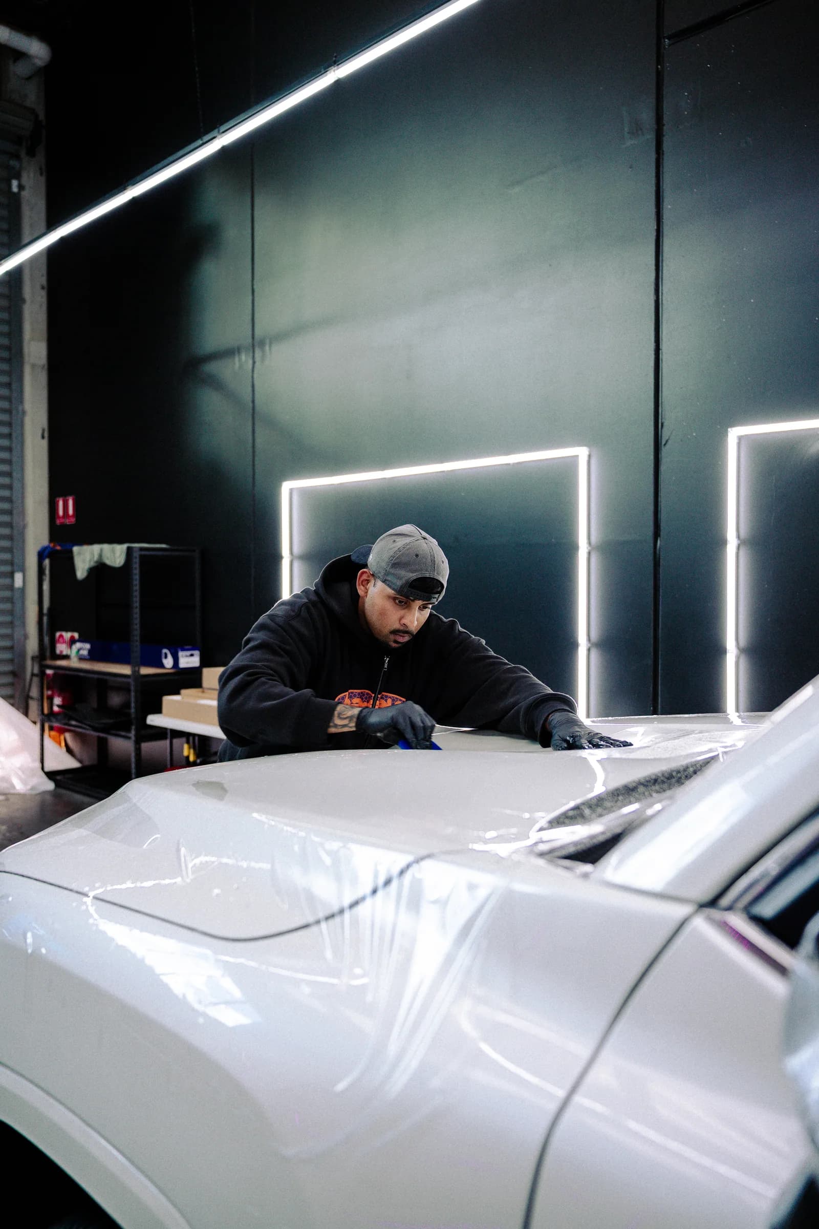 Film being applied to a vehicle at Xotic Customs