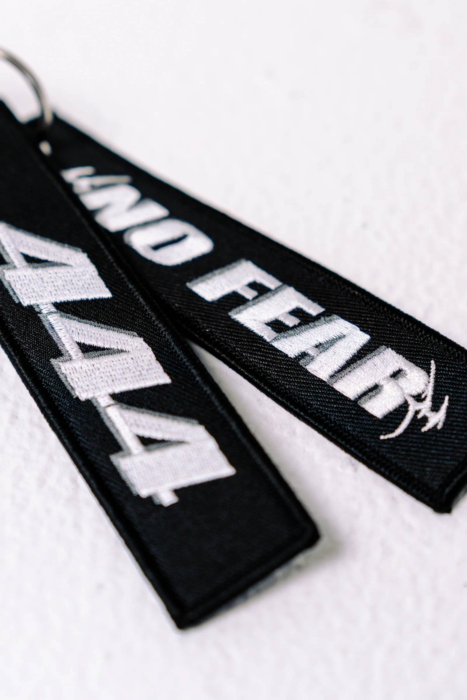 Black 444racingco key tags with white embroidery on a white background