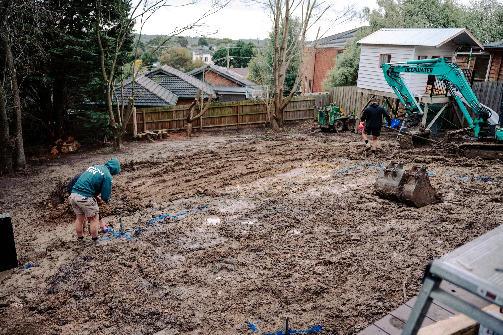 Enchanted Pools workers and an excavator preparing a backyard pool site