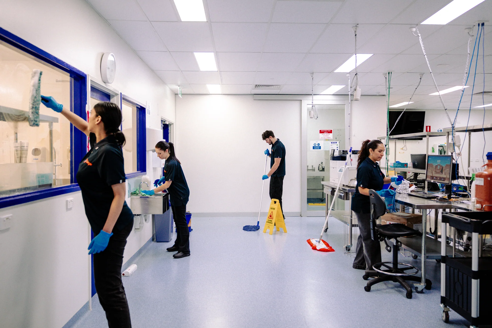 Kango staff cleaning benches, floors and fittings in a commercial facility