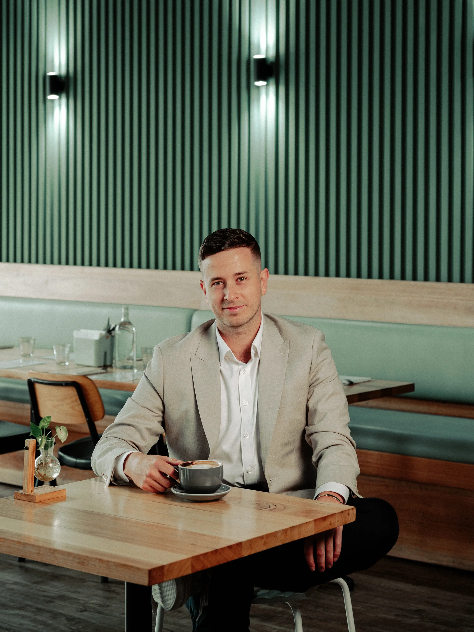 Michael seated beside a coffee against a green cafe banquette