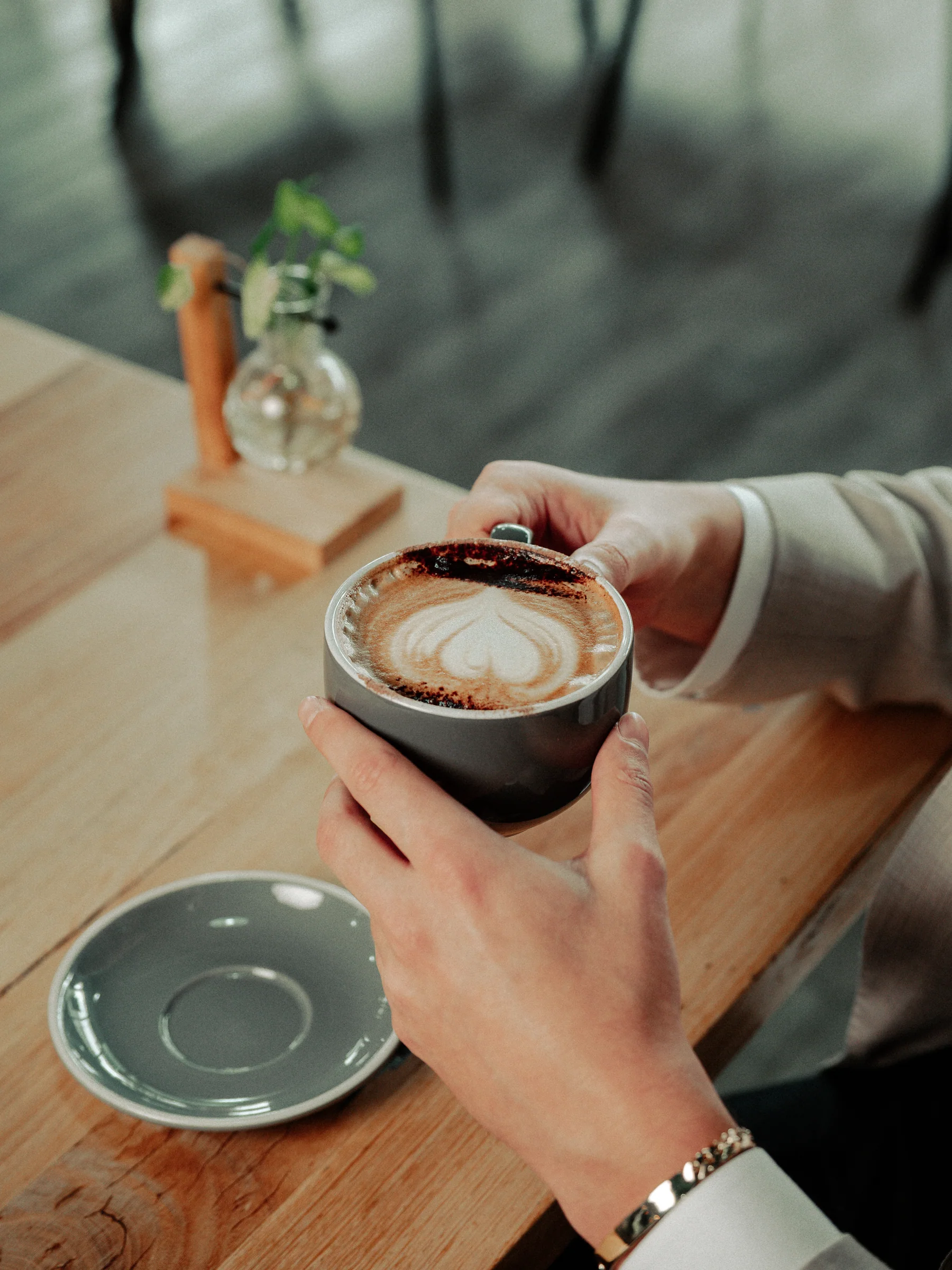 Hands holding a ceramic coffee cup on a cafe table