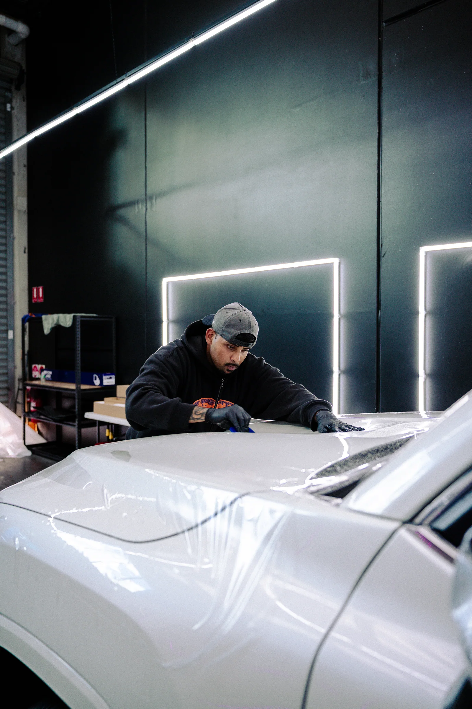 Film being applied to a vehicle at Xotic Customs